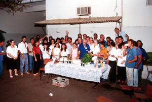 Alderico corta o bolo em sua festa de despedida da Companhia de Telecomunicações do Brasil Central (CTBC), quando se aposentou. Ele trabalhou na empresa durante 32 anos. Ao centro estão o neto Roberto, Alderico e Ana Tostes, sua esposa.