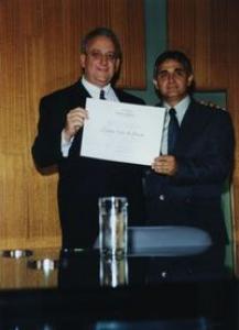 Evauri (à esquerda) recebendo o certificado de Honra ao Mérito de cidadão uberlandense das mãos do vereador Vilmar Resende (à direita).