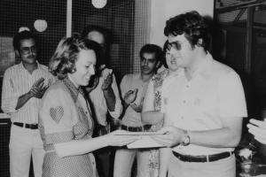Elma, esposa de Dilson, recebendo de um colega homenagem da CTBC por completar dez anos de trabalho na empresa. Atrás, estão outros colegas de trabalho batendo palmas.