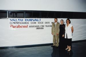 Os três estão de pé, em frente a uma faixa com a inscrição 