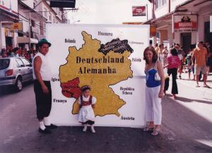 Nínive, criança, no Sommerfest, com seu pai (Rogério de Carvalho) e sua mãe (Erlinéa Degen). 
Seu pai trabalhava na prefeitura e, para esta celebração, fez o mapa da Alemanha com tampinha de garrafa pet. A foto foi tirada na Avenida Presidente Vargas.