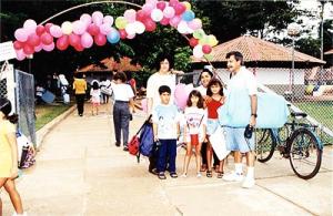Walmira e Vicente Bernardes com filhos Luiz Otávio (de calça azul) e Ana Luiza (blusa vermelha) diante da escola das crianças em Carajás. 1998.