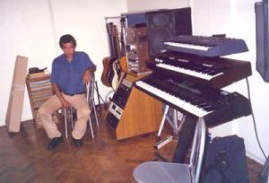Murilo Antunes sentado em uma sala repleta de instrumentos