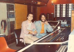 Márcio Borges com o parceiro e compositor mineiro Tunai, à mesa de estúdio de gravação. Tunai é Mineiro de Ponte Nova. Teve as primeiras noções de piano com a mãe. Sua família era ligada à música, e praticamente todos os dez irmãos são ligados ao meio artístico, sendo João Bosco o irmão mais famoso. Aos 11 anos, Tunai chamou a atenção em um festival da escola, cantando bossa nova. Desde então não parou mais de se ligar à música, mesmo quase se formando em engenharia. Suas composições (a maioria em parceria com o letrista Sergio Natureza) já foram gravadas por Milton Nascimento, Emílio Santiago, Fagner, Gal Costa, Simone, Nana Caymmi e muitos outros. O primeiro sucesso foi 