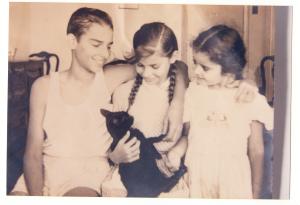 Carlo Leonardo Schneider e as irmãs Dóris e Gracie brincando com um gato.