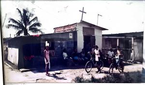 Registro histórico da Igreja Divina Misericórdia, localizada no Ponto Final da Vila Esperança, em Cubatão. A fotografia mostra o templo em sua fase original, construído em madeira, antes das reformas e ampliações que marcaram sua trajetória. Este momento retrata a simplicidade da comunidade e a força da fé que sustentava os moradores da região.