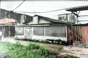 Nesta fotografia, vemos a Igreja da Divina Misericórdia, no Ponto Final da Vila Esperança, já com a cozinha de concreto construída ao fundo. A parte frontal do templo recebeu uma base reforçada para suportar as missas em terreno de mangue, mas as paredes de madeira exigiam manutenção constante. O registro mostra o esforço da comunidade em manter viva sua fé em meio às adversidades ambientais.