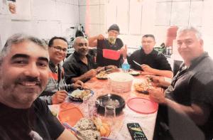 Em selfie, o engenheiro Giba, da obra da Igreja da Divina Misericórdia, na Vila Esperança, durante um dos almoços que reuniam os envolvidos na construção. Vemos Edite servindo a comida, função inicialmente designada pelo padre, mas que logo se transformou em responsabilidade integral dela, símbolo de sua dedicação.