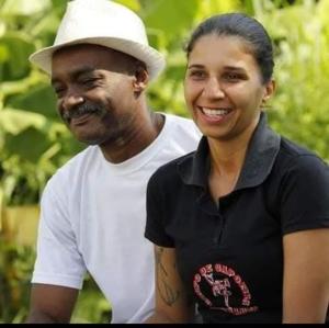 Patrícia, conhecida como Narizinho, integrante do Grupo de Capoeira Arte e Luta, aparece ao lado do Mestre Geraldo, seu padrinho e figura paterna, fundador do Grupo Meninos Guerreiros. A fotografia foi realizada durante uma entrevista sobre a capoeira em Cubatão, no contexto da pandemia. O registro documenta a transmissão de saberes, a ancestralidade e a resistência da capoeira como prática cultural, educativa e comunitária.