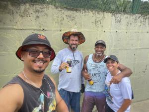Patrícia, ao lado do marido Cláudio, Waldir Grisólia Júnior (Age Ação Visual) e Davis Santos Miranda, o Deivs One, registra em selfie um instante de pausa. O muro, ainda em esboço, guarda a promessa de cores e formas que logo florescerão. Entre riscar linhas e saborear um guaraná, os artistas revelam a simplicidade e a intensidade do processo criativo: energia compartilhada, cumplicidade e a certeza de que a arte é também sobre encontros. A fotografia eterniza esse momento de descontração e força coletiva, em dezembro de 2024.