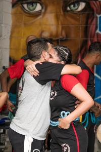 Patrícia com o irmão Fábio, o Mestre Cabrito, na sua formatura na capoeira, o que ganha ainda mais significado. O abraço registrado na fotografia é símbolo de fraternidade, cumplicidade e força compartilhada. Mais do que um rito individual, é a celebração de laços que se constroem dentro e fora da roda, reafirmando que a capoeira é também família.