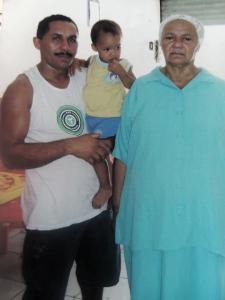 Registro feito na Vila Esperança, que reúne três gerações da mesma família: Alfredo, seu filho Artur ainda bebê, e sua mãe, Dona Zefa. A imagem foi feita durante uma visita da mãe ao filho, em um momento em que Alfredo já havia conquistado maior estabilidade de vida com o Cabeça’s Bar, localizado na Avenida Principal da comunidade. A fotografia expressa pertencimento, orgulho e continuidade familiar.