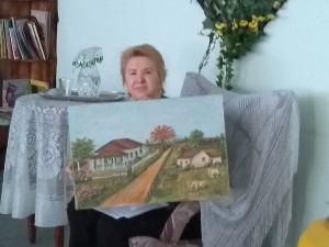 Dona Rosa mostra o quadro que pintou da casa onde passou sua infância