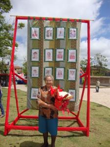 personagem: Dona Alaide<br>historia: Dona Alaíde em frente a colcha de retalhos<br>