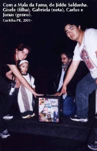 personagem: Gisele (filha), Gabriela (neta), eu e Jonas (genro)<br>historia: Nós quatro seguramos a MALA DA FAMA, trabalho do multiartista Jiddu Saldanha, no Largo da Ordem, Curitiba-PR.<br>