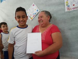 DONA MARILEI RECEBENDO O DESENHO DO ALUNO DO 4º ANO A