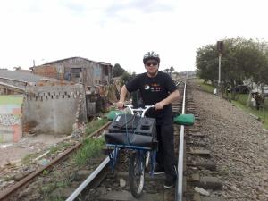 Atravessando a linha do trem com a bike e o teatro de bonecos na garupa