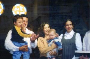 Foto tirada no dia batizado do irmão mais novo do Vitor. Vitor está no colo do seu pai e seu irmão está no colo de sua mãe.