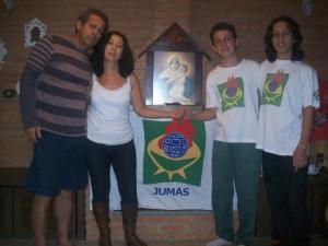 Esta é a foto mais atual de toda a família reunida. Na foto estão o pai, a mãe, o irmão e o Vitor. Estão reunidos em volta da imagem da Nossa Senhora e do Menino Jesus e da bandeira do grupo JUMAS [Juventude Masculina de Schoenstatt], que é um ramo do Movimento Apostólico de Schoenstatt, grupo religioso do qual a família faz parte.