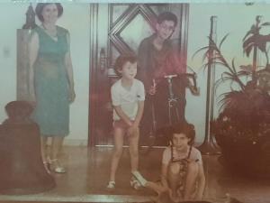 Esta foto foi tirada dentro da casa da mãe do André. Na foto está o André, o menino mais novo em pé; sua irmã Paula brincando com o Johnny, o cachorro;  seu irmão José na bicicleta e uma amiga de sua mãe.