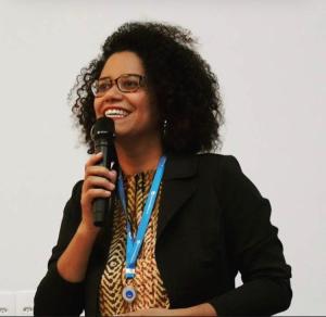 Milca durante um evento sobre o Dia Internacional da Mulher, em 8 de março de 2018, no Paraná Banco. Essa fotografia marca um momento importante da carreira de Milca, que representa seu início em D&I e o primeiro ano de eventos com foco em Diversidade.