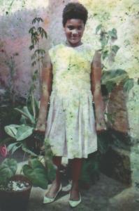 Regina na casa de dona Doca, vizinha de frente. Regina lembra-se que era uma casa bonita, com um quintal cheio de flores. Estava passando pela rua o binoqueiro e, como a família de Regina não tinha dinheiro, a dona Doca falou para Regina colocar o melhor vestido, colocar um sapato (o melhor era de sua irmã) e a mandou tirar a foto. Antiga Rua 13, Atual Rua Serpa Brandão. Vila Munhoz, São Paulo.