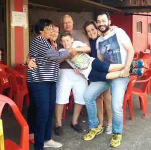 Guilherme e sua família, durante um encontro, num bar em São Carlos, SP. Da esq. para dir., sua tia paterna e segunda mãe Sônia, sua mãe Ida, seu pai José Afrânio, seu sobrinho Enzo, sua irmã Carol e ele. Essa fotografia é uma releitura de uma anterior, tirada seis anos antes. Guilherme conta que o nascimento de Enzo foi importante para reestabelecer a união familiar.