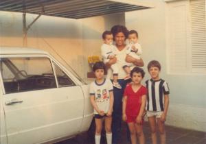 Maria Helena segurando os gêmeos Adilson e Alexandre. Abaixo estão algumas crianças da rua que gostavam de ir à casa de Yara, mãe dos bebês. Yara foi quem tirou esta foto e Maria Helena se recorda de um bolo de chocolate que Yara tinha feito.