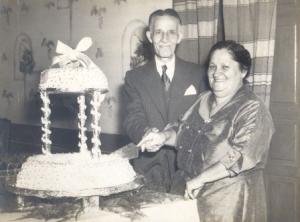 Nicolau e Serafina (pais de Thereza) cortam o bolo em comemoração aos quarenta anos de casamento, na sala de jantar da casa onde moravam.