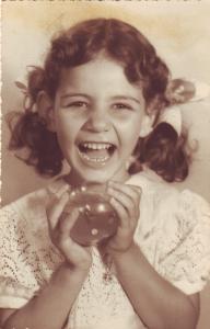 Anna sorrindo em foto de infância.