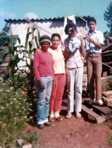 Da esquerda para direita: Josefa (mãe) com os vizinhos Dalva, Manoel, Manoela (criança). Foto do início da ocupação do bairro Americanópolis, atrás pode-se ver uma moradia e material usado na construção de novas moradias.