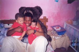 Eduardo abraça os filhos Natan e Eduarda em um quartinho cedido por sua mãe, onde a família morou seis anos, no Jardim Vista Alegre.