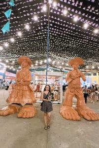 Em julho de 2025, Sandra e o cachorrinho Dean participam de uma grande festa junina no Centro Cultural do Turista, em Aracaju. Posicionados diante das esculturas de Lampião e Maria Bonita, a imagem conecta a celebração popular nordestina ao início de uma viagem especial: a comemoração da aposentadoria de Vagner, esposo de Sandra. O registro une memória cultural, turismo e vida familiar em um mesmo instante.
