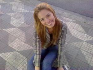 Dayana posa em uma calçada típica da cidade de São Paulo. A imagem associa o espaço urbano ao cultivo de sonhos, revelando a cidade como solo fértil para projetos de vida.