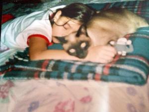 Raissa, com cerca de sete ou oito anos, dorme ao lado de Samy, a gatinha da família, na cama de seus pais. O descanso acontece durante a tarde, em um momento de pausa compartilhada. O apartamento retratado foi o lar de Samy durante toda a sua vida e também o espaço onde Raissa viveu grande parte da própria história. A fotografia preserva a intimidade de um cotidiano construído lentamente, entre sono, cuidado e pertencimento.