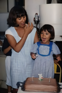 A foto foi tirada na máquina de bobina, na casa da Vila A, onde Rafaela morava em frente à pista de terra para bikers. Era seu primeiro aniversário após a adoção, marcado pelo momento em que sua mãe lhe entregou um pacote transparente com um vestido azul, semelhante ao dela. Rafaela, que não falava muito, apenas observava e pensava, sentindo a felicidade da mãe ao vê-la igual a ela. O bolo era o tradicional chiffon, receita da avó materna que passou para sua mãe e depois para Rafaela, que aprendeu aos 11 anos e, até então, era a única a saber fazê-lo. O diferencial estava em molhar a massa com guaraná e cobrir com chocolate do padre ou Nestlé. Mais tarde, ao se mudar para Fortaleza e São Paulo, Rafaela deixou de preparar o bolo e nunca mais o fez.