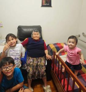 Em um almoço familiar, Marina celebra a presença de sua mãe, a bisavó Tihio, de 93 anos, e de seus netos Elisa, Daniel e Isadora. Marina registra essa memória, fortalecendo os laços afetivos e a memória familiar.