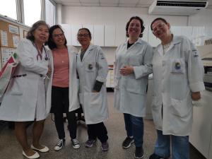 Marina aparece ao lado das funcionárias biomédicas do Laboratório de Exames do Ambulatório Quarteirão da Saúde, em Diadema. O registro marca o período de sua aposentadoria, cercada por colegas prestativas e dedicadas, que fizeram parte de sua trajetória profissional. A fotografia guarda a memória de um ciclo que se encerra, revelando o afeto e o reconhecimento construídos no cotidiano de trabalho e na convivência com a equipe.