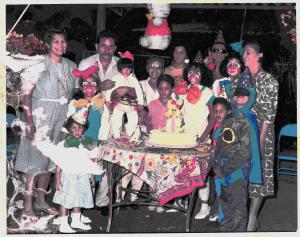 A fotografia registra o primeiro aniversário de Oriana, celebrado no quintal da casa onde vivia à beira do Lago de Maracaibo. Vestida com uma fantasia de coelho, que nem todas as irmãs e primos apreciaram , ela guarda dessa imagem um afeto especial: acha-se fofa e reafirma um carinho duradouro pelos coelhos. Estão presentes seus pais, Nieves Hernández e José Rafael; as irmãs María Fernanda, María Cristina e María Alejandra; os avós Blanca, Luisa e Alejo (Alejandro); a tia María Luisa (Maya); e os primos Bárbara, Félix, Leonel, Miguel e Juan (Chiche). A cena reúne gerações em torno de um rito íntimo, onde infância, fantasia e afeto se entrelaçam.