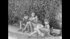 Fotografia de Louis Robin e de seus irmãos reunidos no quintal. Da esquerda para a direita, Édouard Henri, Celina Marie, Louis Robin e Jean Paul aparecem sentados junto às plantas do jardim, acompanhados de seus brinquedos.