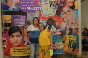 Filha Jackeline, à esquerda e professora Holanda, à direita. As duas em frente a uma cartaz de empoderamento feminino, em março de 2020.