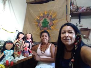 Nesta foto Luakam estava acompanhada da Presidente da Associação Indígena da Aldeia Maracanã, a professora Marise (Pararipe). Luakam tem o hábito de receber indígenas em sua casa para falarem sobre as Bonecas Anaty. Juntos, gravam vídeos para divulgarem na internet. Nesse dia elas gravaram um vídeo para mostrar para o povo que as bonecas são legalizadas e que os indígenas estão de acordo e se sentem representados por elas.
As bonecas da foto representam as etnias (esq. para dir.) Anambé, Krahô, Kamaiurá e Caiapó.