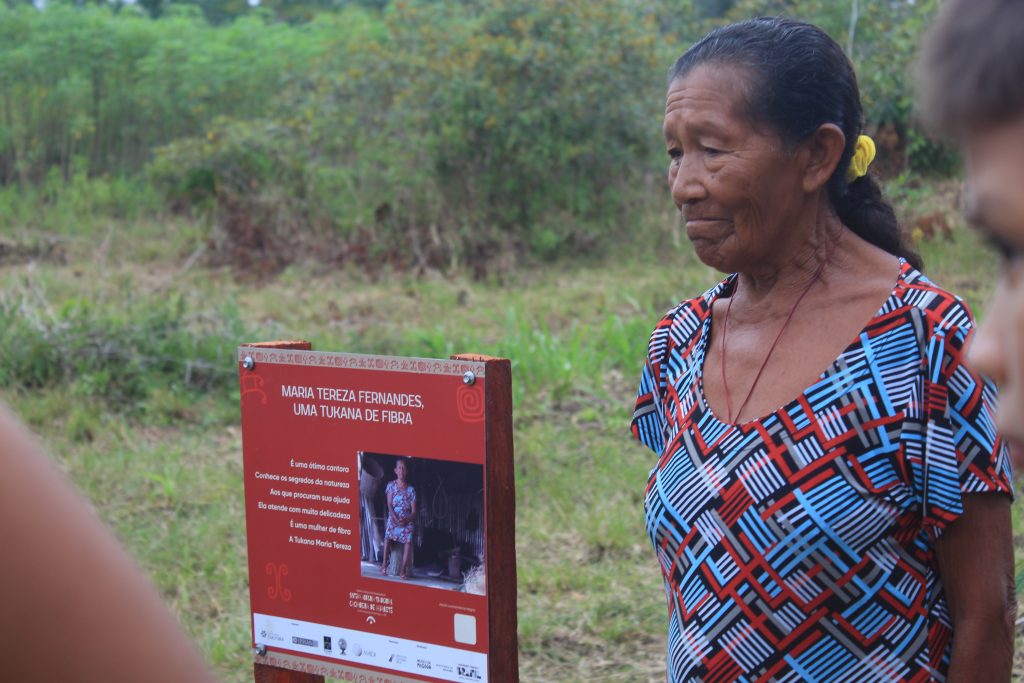 Dona Maria Tereza posando pra foto ao lado da placa em sua homenagem